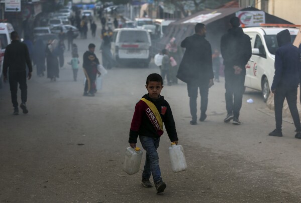 طفل فلسطيني نازح بسبب الهجوم البري الإسرائيلي على قطاع غزة يحمل صفائح في مخيم مؤقت في رفح، قطاع غزة، الاثنين، 19 فبراير، 2024. (AP Photo/Mohammed Dahman)