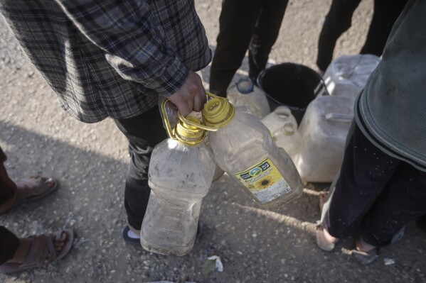 فلسطينيون نزحوا بسبب الهجوم البري الإسرائيلي على قطاع غزة يصطفون للحصول على المياه في مخيم مؤقت في رفح، قطاع غزة، الاثنين، 19 فبراير، 2024. (AP Photo/Mohammed Dahman)