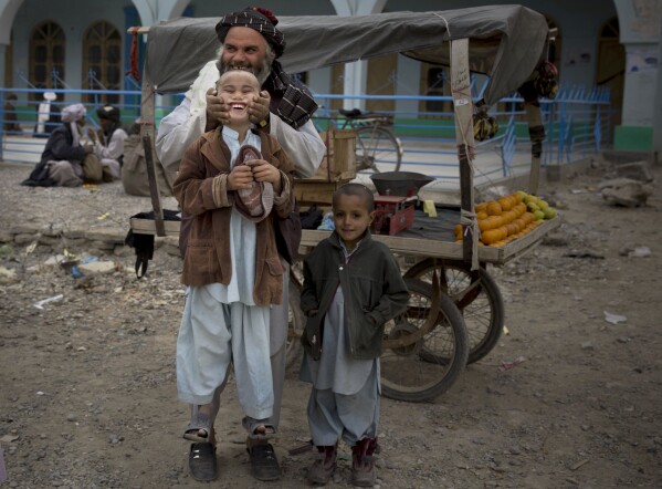 ملف – بائع فاكهة يرفع ابنه من خديه في وسط قندهار، أفغانستان، 12 مارس، 2014. (AP Photo/Anja Niedringhaus, File)