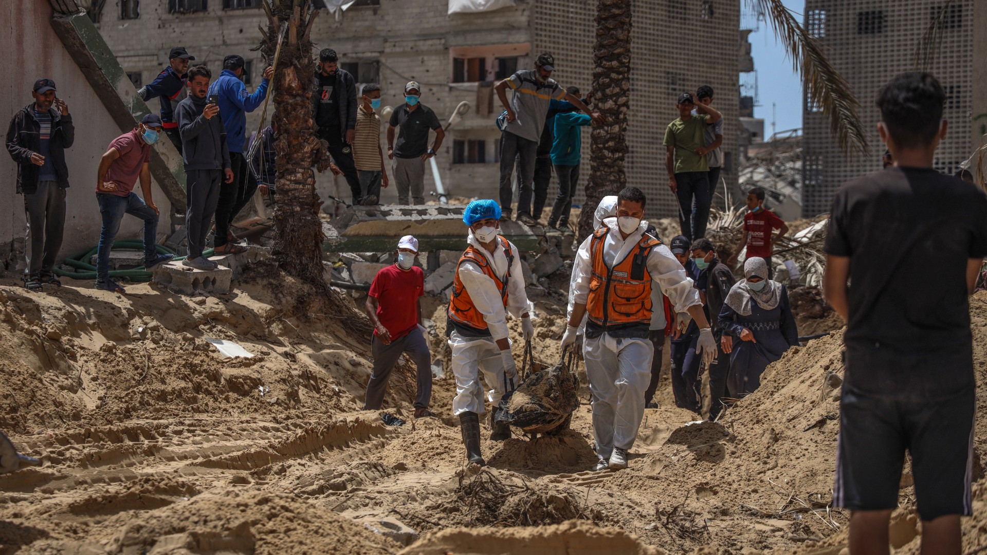 أشخاص وعاملون صحيون ينتشلون الجثث التي عثر عليها في مستشفى ناصر في خان يونس في 23 نيسان/أبريل (أ ف ب)