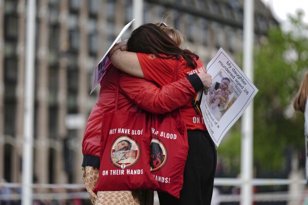 نشطاء الدم الملوث يتعانقون خلال تجمع في ساحة البرلمان، قبل نشر التقرير النهائي حول الفضيحة، في لندن، الأحد 19 مايو 2024. سيتم نشر التقرير النهائي للتحقيق في الدم الملوث في المملكة المتحدة يوم الاثنين، بعد ست سنوات بدأت عملها.  واستمع التحقيق إلى أدلة حول كيفية إصابة آلاف الأشخاص بفيروس نقص المناعة البشرية أو التهاب الكبد نتيجة عمليات نقل الدم الملوث ومنتجات الدم في السبعينيات والثمانينيات.  (آرون تشاون / PA عبر AP)