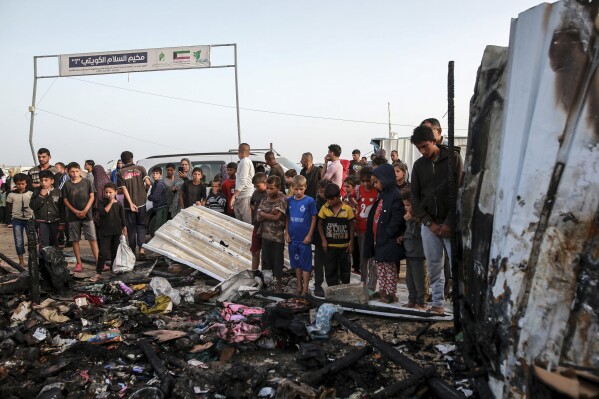 فلسطينيون ينظرون إلى الدمار بعد غارة إسرائيلية حيث كان يقيم النازحون في رفح، قطاع غزة، يوم الاثنين 27 مايو 2024. قال العاملون في مجال الصحة الفلسطينيون إن الغارات الجوية الإسرائيلية قتلت 35 شخصًا على الأقل في المنطقة.  وأكد الجيش الإسرائيلي غارة يوم الأحد وقال إنها أصابت منشأة تابعة لحماس وقتلت اثنين من كبار نشطاء حماس.  (صورة AP/جهاد الشرفي)