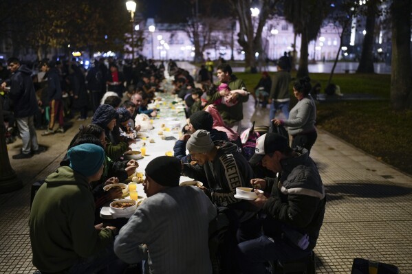 أشخاص يتناولون وجبات الطعام التي تقدمها منظمة Red Solidaria في ساحة بلازا دي مايو، أمام مقر الحكومة، في بوينس آيرس، الأرجنتين، 6 يونيو، 2024. (AP Photo/Natacha Pisarenko)