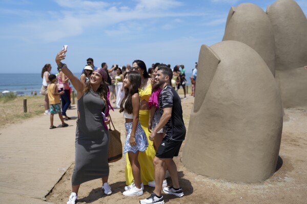 السياح يطرحون على صورة سيلفي من قبل "La Mano" Sculpture في Punta Del Este ، أوروغواي ، الثلاثاء ، 28 يناير ، 2025. (AP Photo/Matilde Campodonico ، ملف)