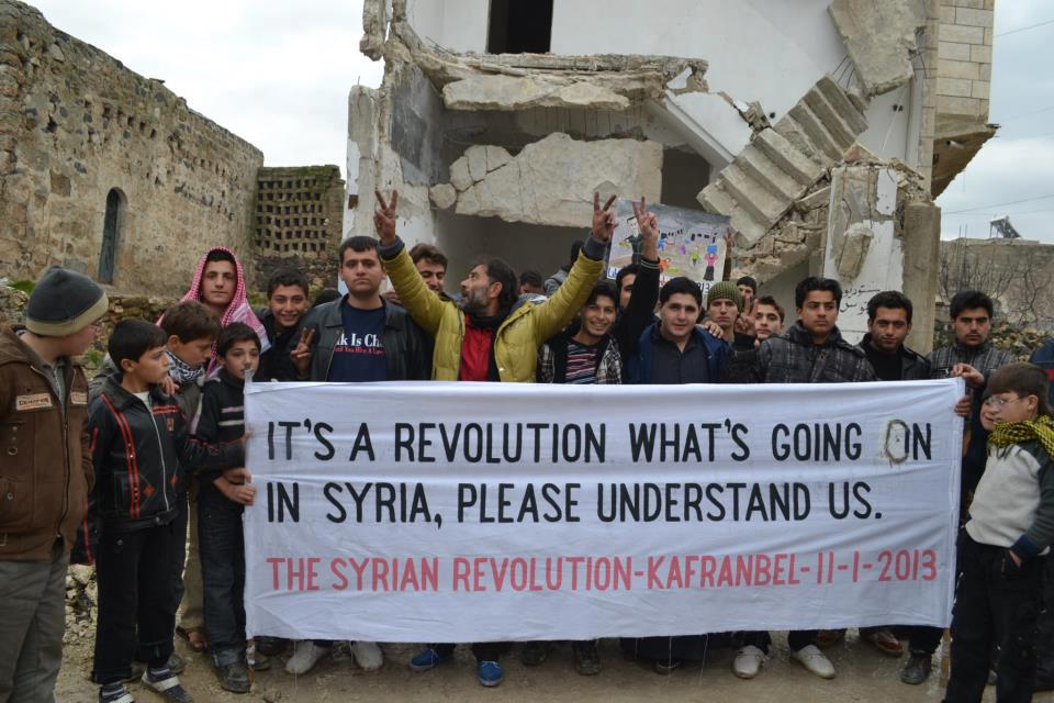 يمسك نشطاء Kafranbel لافتة لدعم الثورة السورية في عام 2013 (Facebook)