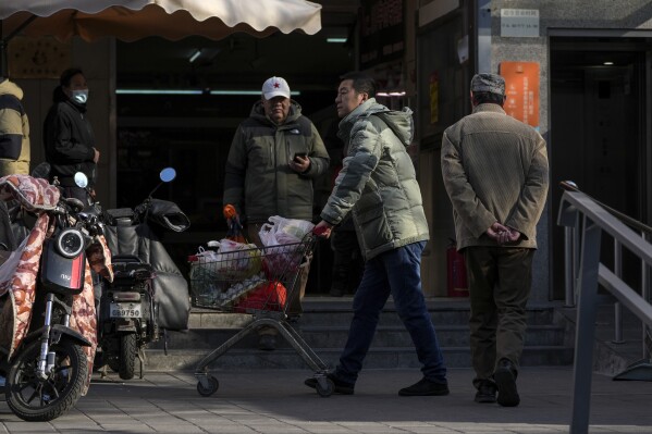 رجل يدفع محملاً ببقالة اشترى من سوبر ماركت في بكين في 26 فبراير 2025. (AP Photo/Andy Wong)