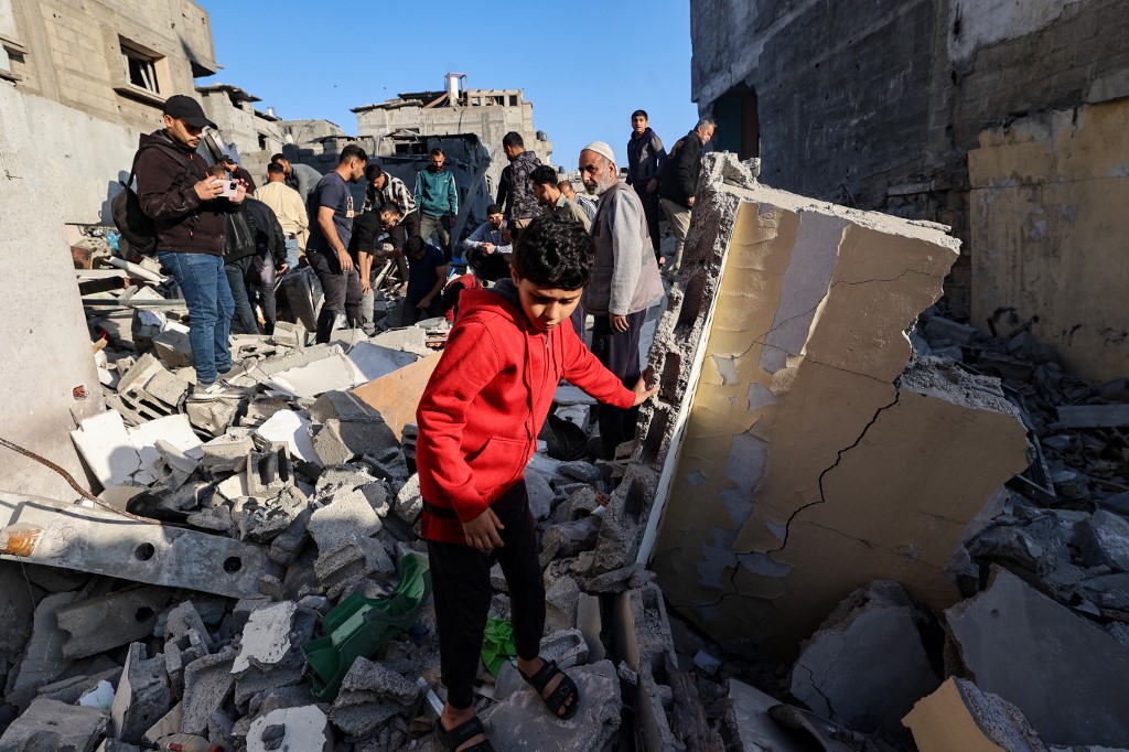 ينظر الطفل إلى أن الناس يبحثون عن الناجين في أنقاض مبنى ضرب في ضربة إسرائيلية في معسكر بوريج للاجئين الفلسطينيين في قطاع غزة الوسطى في 2 مايو ، 2025. (AFP)