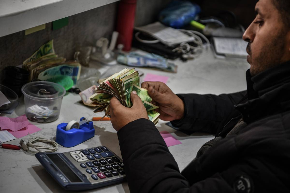 يحسب الموظف أموالًا في مكتب Exchange كهجمات إسرائيلية على غزة إلى جانب الحصار ، ويتسبب في قضايا حول العملات الأجنبية وتزويد Shekel في Rafah ، غزة في 06 فبراير 2024 (Abed Zagout - Anadolu Agency)