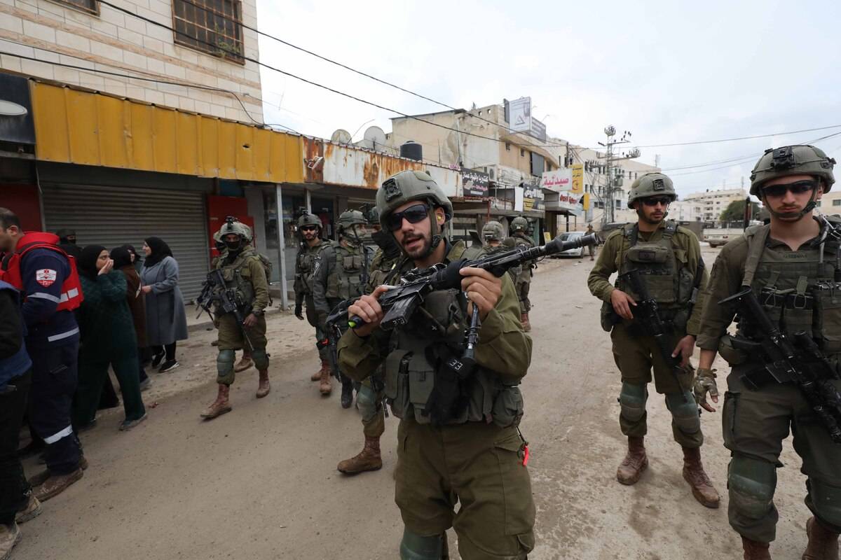 يجتمع الفلسطينيون عند المدخل الرئيسي لمعسكر جينين للاجئين حيث يمنع الجيش الإسرائيلي الآلاف من الفلسطينيين من العودة إلى منازلهم في جينين ، الضفة الغربية في 19 فبراير 2025.