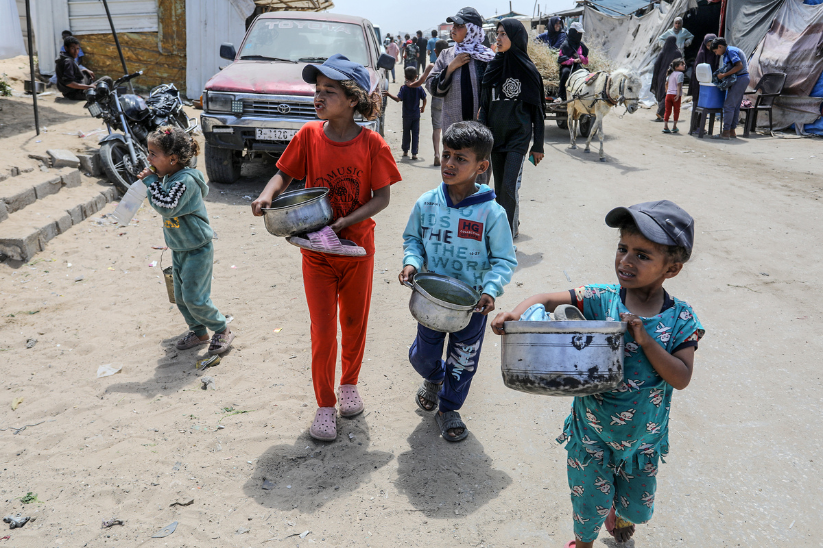 الفلسطينيون النازحون ، بمن فيهم الأطفال ، يتجمعون لتلقي وجبات ساخنة وزعتها الجمعيات الخيرية في منطقة ماواسي في خان يونيس ، جنوب غزة ، في 3 مايو 2025 (عابد رحيم خاتيب - وكالة أندمولو)