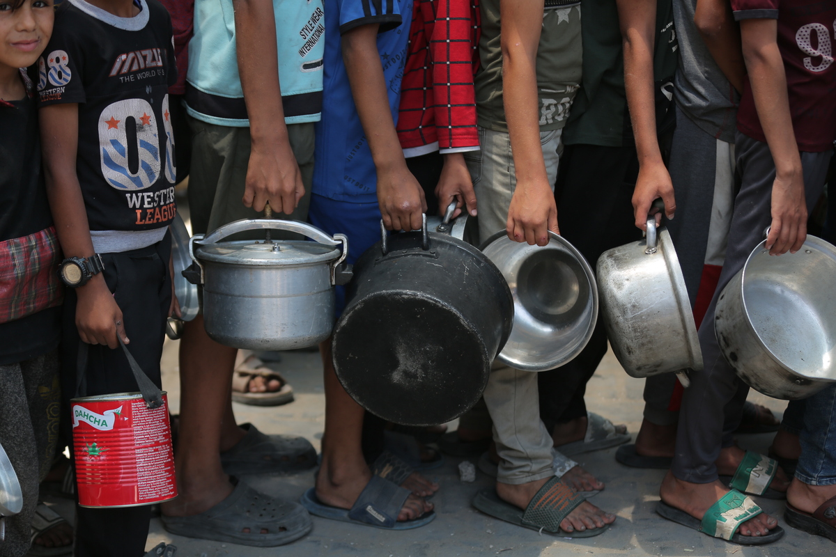 ينتظر الفلسطينيون ، بمن فيهم الأطفال ، الذين يكافحون مع الجوع ، في طابور لتلقي وجبات ساخنة وزعتها المنظمات الخيرية بينما تستمر هجمات إسرائيل المدمرة على قطاع غزة مع الأزمة الإنسانية في المنطقة في المنطقة)