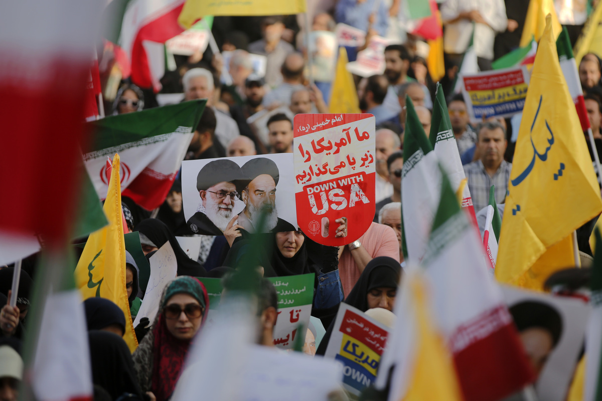 الناس ، الذين يحملون لافتات وأعلام ، يجتمعون للاحتفال بوقف إطلاق النار بين إيران وإسرائيل أثناء تجمعهم في ميدان الثورة في طهران ، إيران في 24 يونيو 2025.