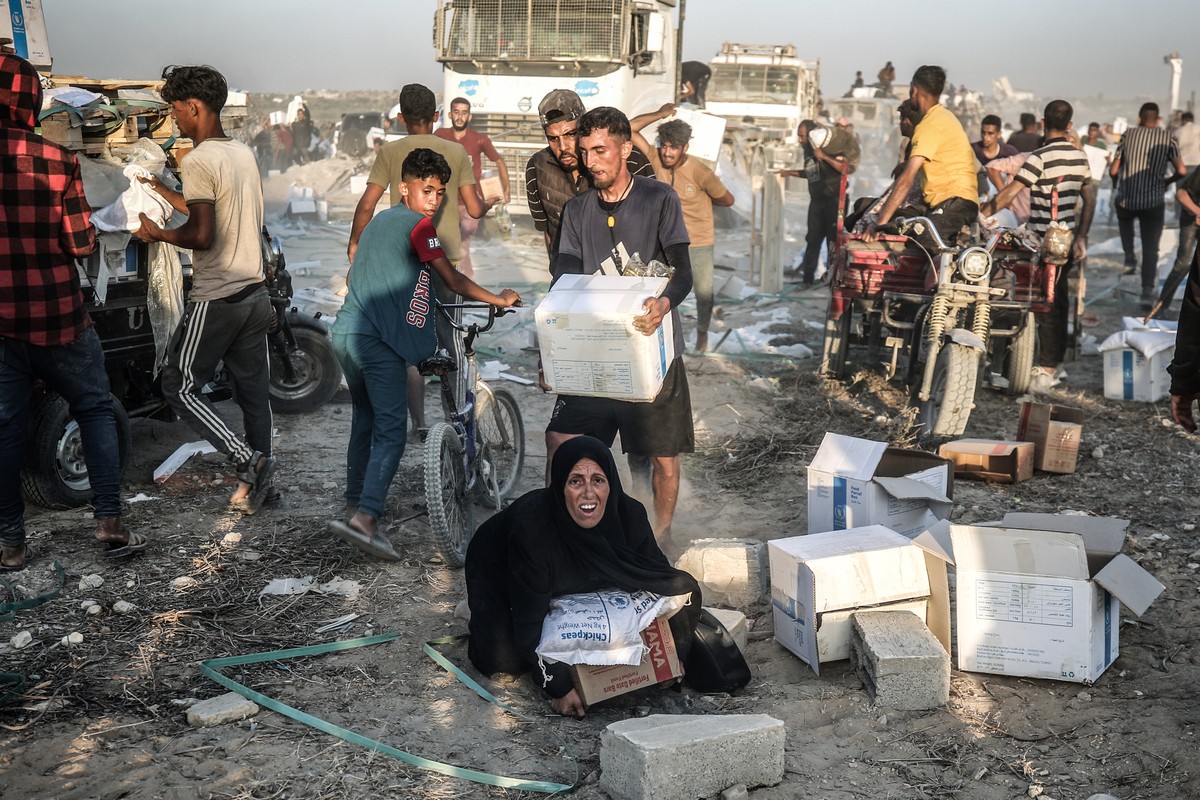 يتلقى الفلسطينيون إمدادات المساعدات بعد أن دخلت شاحنات المساعدة عبر ممر Netzarim في ظل هجمات إسرائيلية في قطاع غزة في 26 يونيو 2025 (علي جاد الله - وكالة Anadolu)