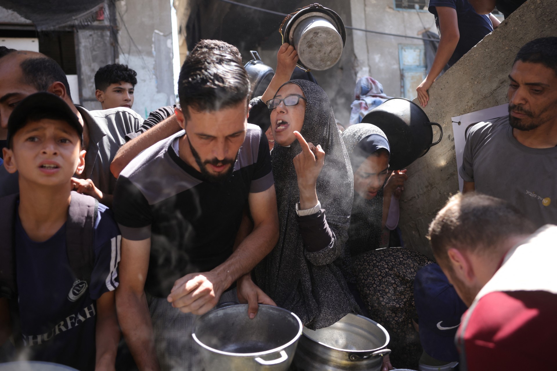 يصطف الفلسطينيون لتلقي وجبة ساخنة في نقطة توزيع الطعام في مدينة غزة في 27 يونيو 2025 (AFP/Bashar Taleb)