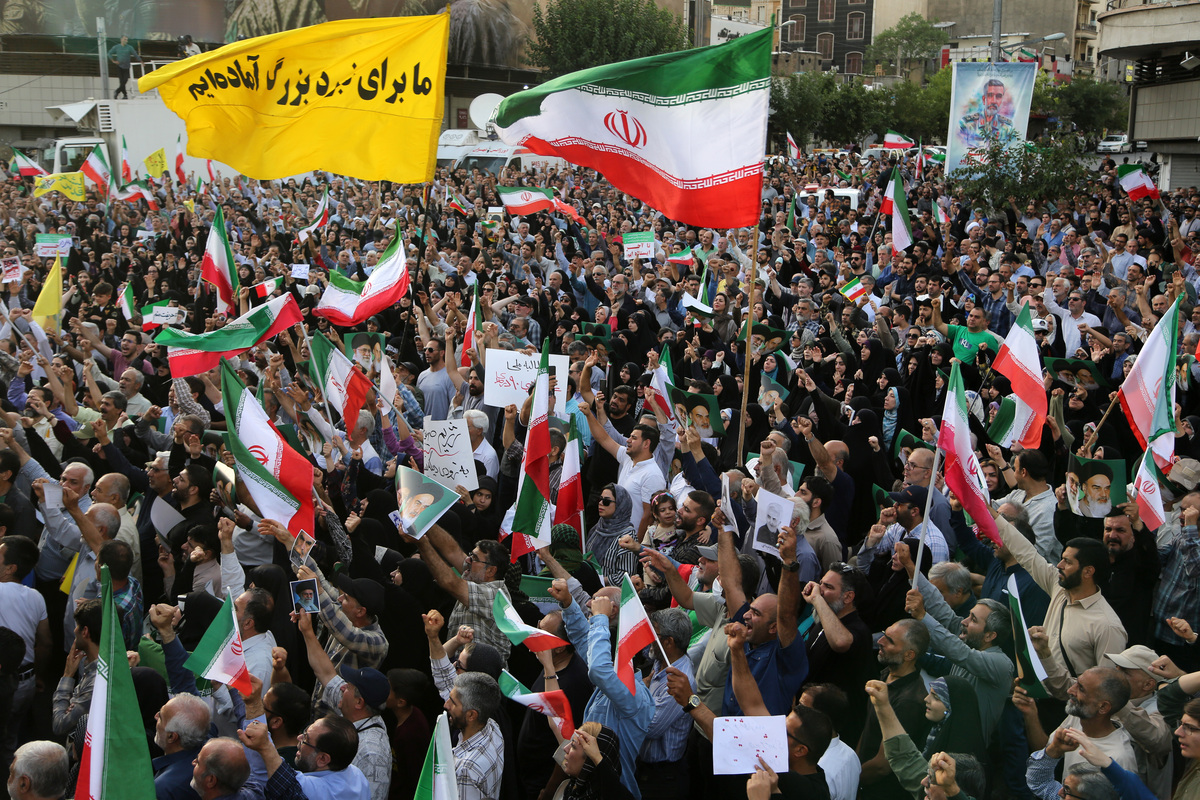 تجمع الحشود التي تحمل الأعلام الإيرانية في ميدان الثورة في العاصمة طهران للاحتجاج على الهجمات الأمريكية على ثلاثة منشآت نووية في إيران في 22 يونيو 2025.