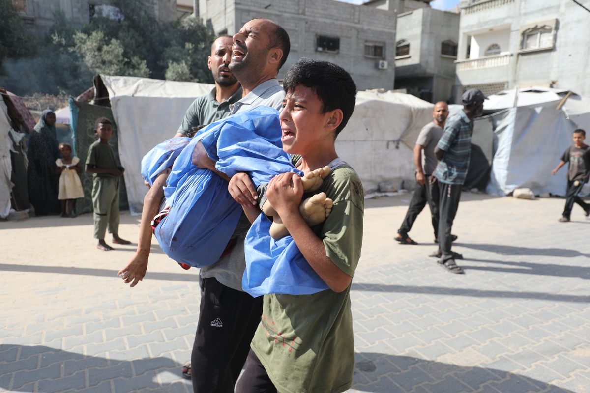 رجل فلسطيني يحمل جسمًا دمويًا للطفل إلى مستشفى ALDA بعد الهجوم الإسرائيلي الذي ضرب نقطة إعادة ملء المياه التي تنتمي إلى الفلسطينيين النازحين في منطقة