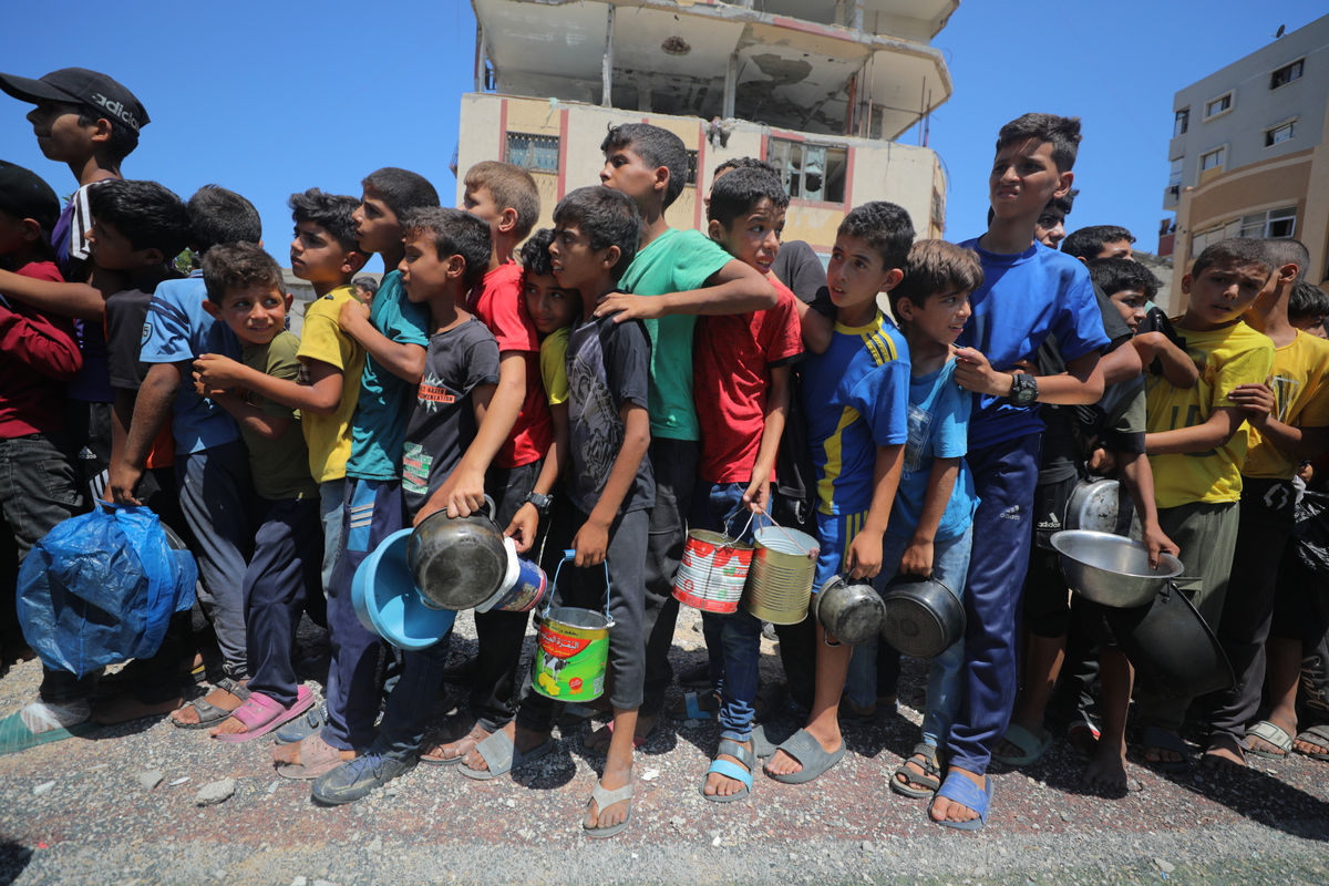 تقوم مؤسسة خيرية بتوزيع وجبات ساخنة على الفلسطينيين الذين يواجهون صعوبات في الوصول إلى الطعام بسبب هجمات إسرائيل المستمرة على قطاع غزة في 13 يوليو 2025 (حسن جيدي - وكالة أنادوولو)