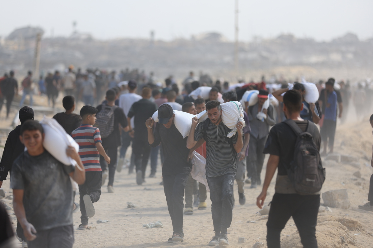 يحمل الفلسطينيون المساعدات التي تم الحصول عليها في زيكيم مع عودة أسرهم بالقرب من السودانيا في شمال غزة في 20 يوليو 2025.
