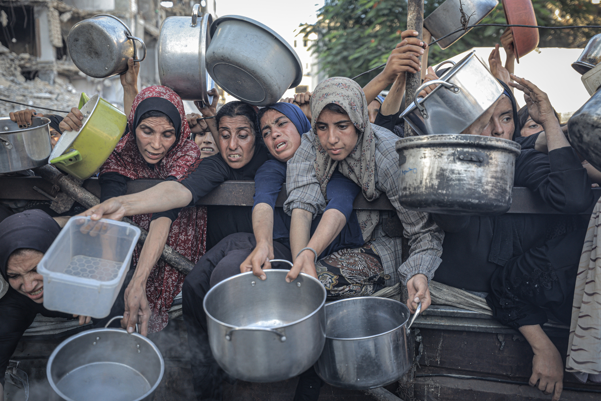 فلسطينيون ، بمن فيهم الأطفال ، الذين يكافحون للوصول إلى الطعام بسبب الحصار الإسرائيلي والهجمات المستمرة على قطاع غزة ، ينتظرون في طابور لتلقي وجبات ساخنة موزعة من قبل المنظمة الخيرية في مدينة غزة ، غزة في 20 يوليو 2025.