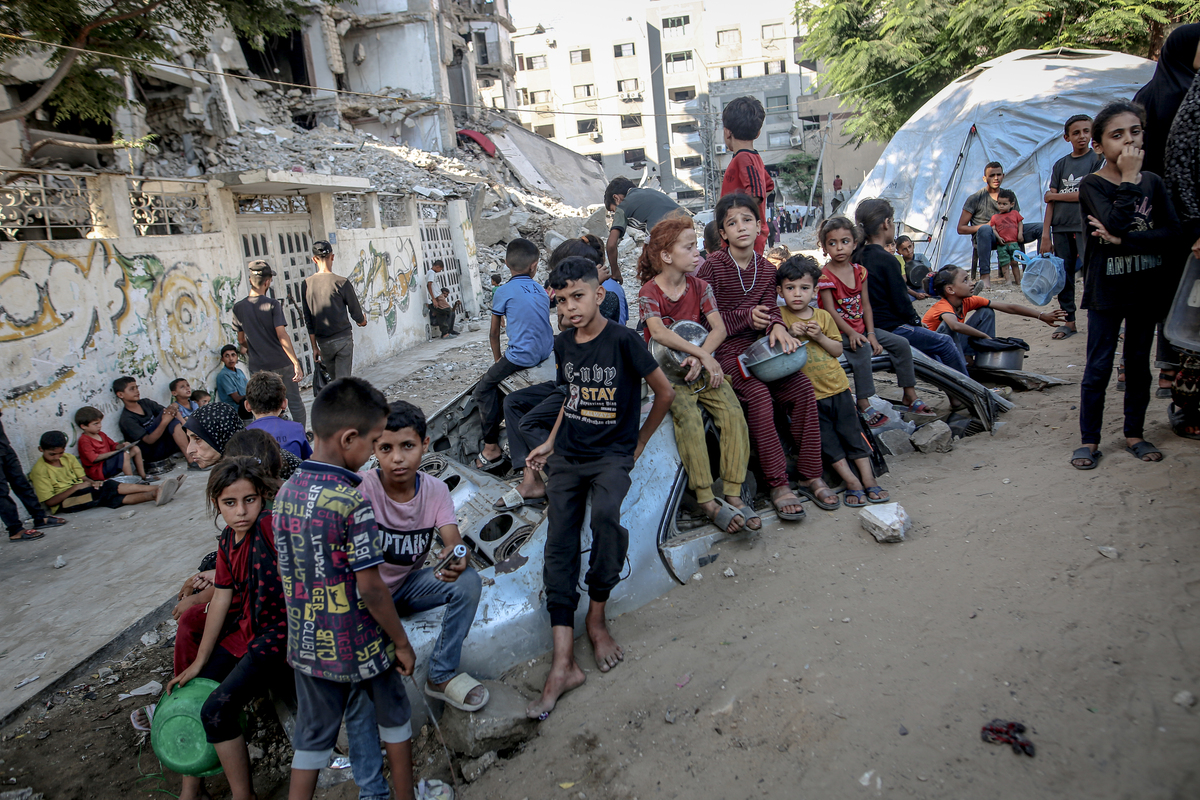 الفلسطينيون الذين يحملون المقالي ، يجتمعون لتلقي وجبات ساخنة ، وزعت من قبل منظمة خيرية في مدينة غزة ، حيث يكافح السكان للوصول إلى الطعام بسبب الحصار الإسرائيلي المستمر والهجمات في مدينة غزة ، غزة في 23 يوليو 2025.