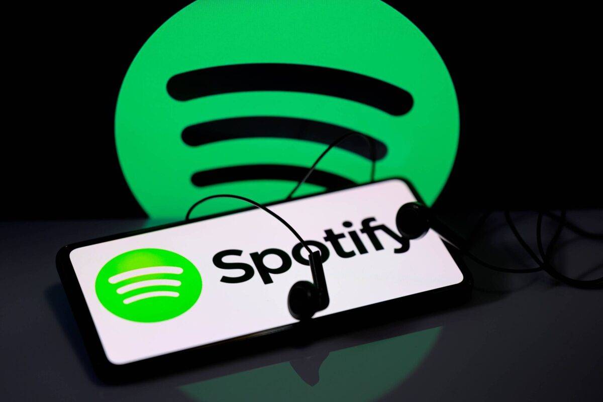 يتم عرض شعار Spotify على هاتف ذكي مع أيقونة Spotify مرئية في الخلفية ، في 11 فبراير 2024. (Jonathan Raa/Nurphoto عبر Getty Images)