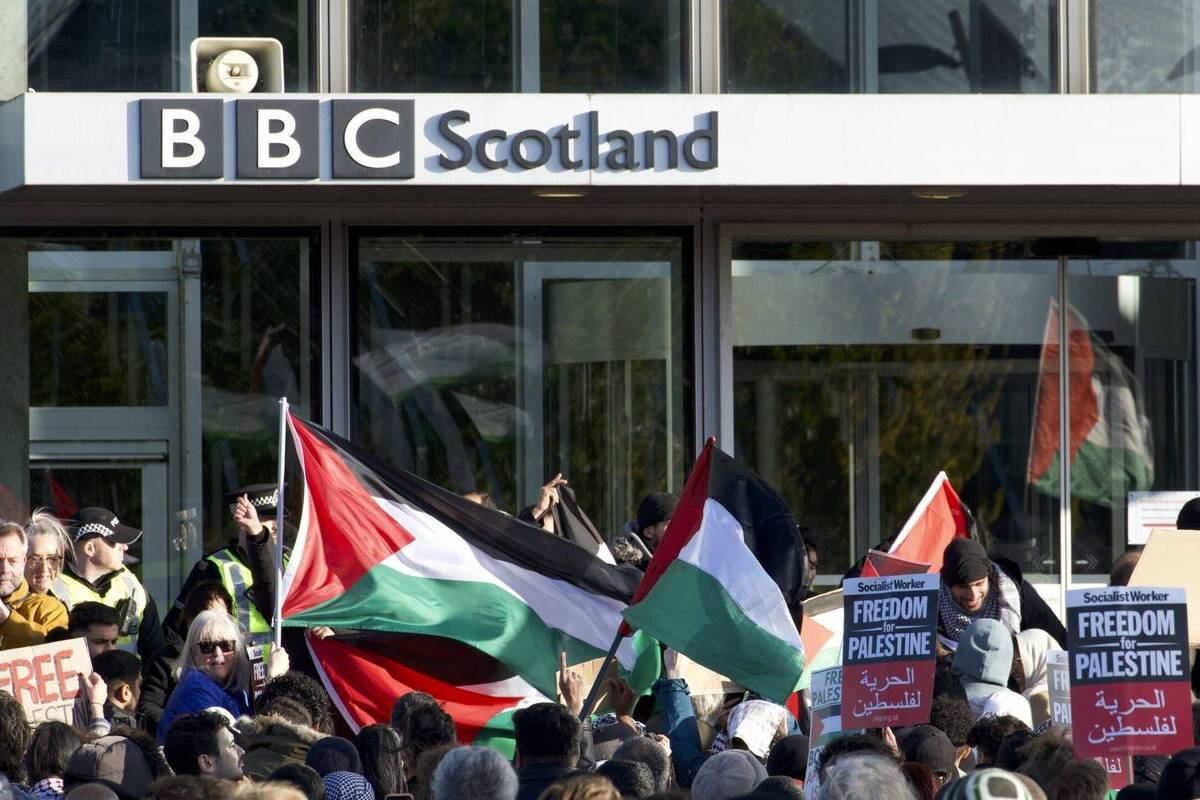 الناس يحملون الأعلام واللافتات الفلسطينية خلال مظاهرة لدعم الفلسطينيين أمام استوديو بي بي سي في غلاسكو ، اسكتلندا في 14 أكتوبر 2023 (أحمد فيفزي أركان - وكالة أنادوولو)