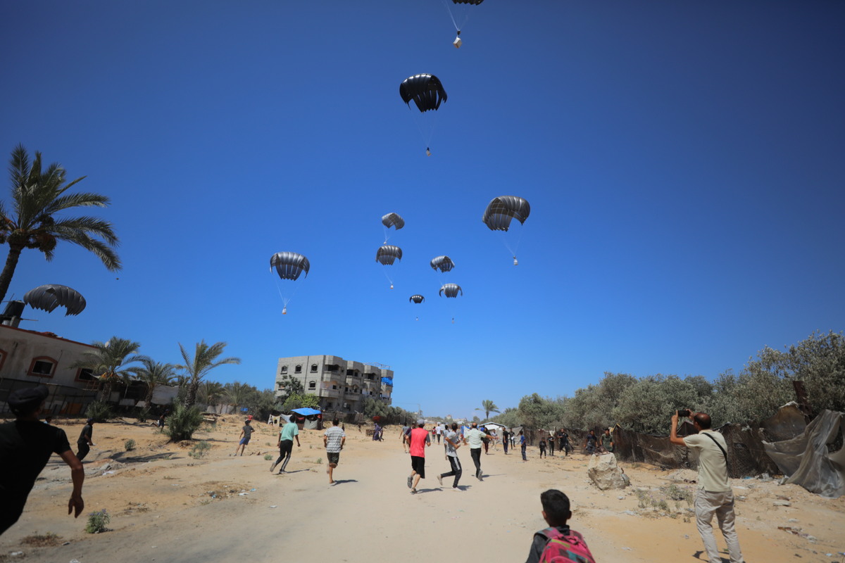 يتجمع الفلسطينيون لجمع المساعدات الإنسانية التي أسقطتها المظلة في منطقة الزاويدا في دير الراهب ، غزة ، في 31 يوليو 2025.
