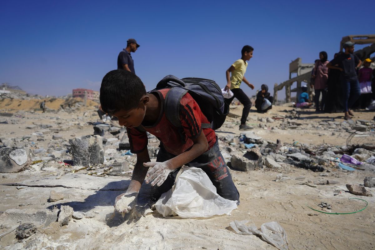 يحاول طفل أن يجمع الدقيق على الأرض بينما يتلقى الفلسطينيون ، الذين يكافحون مع الجوع ، قدرًا محدودًا من الدقيق في نقطة توزيع المساعدات الإنسانية في معبر الحدود Zikim في غزة في 1 أغسطس 2025.