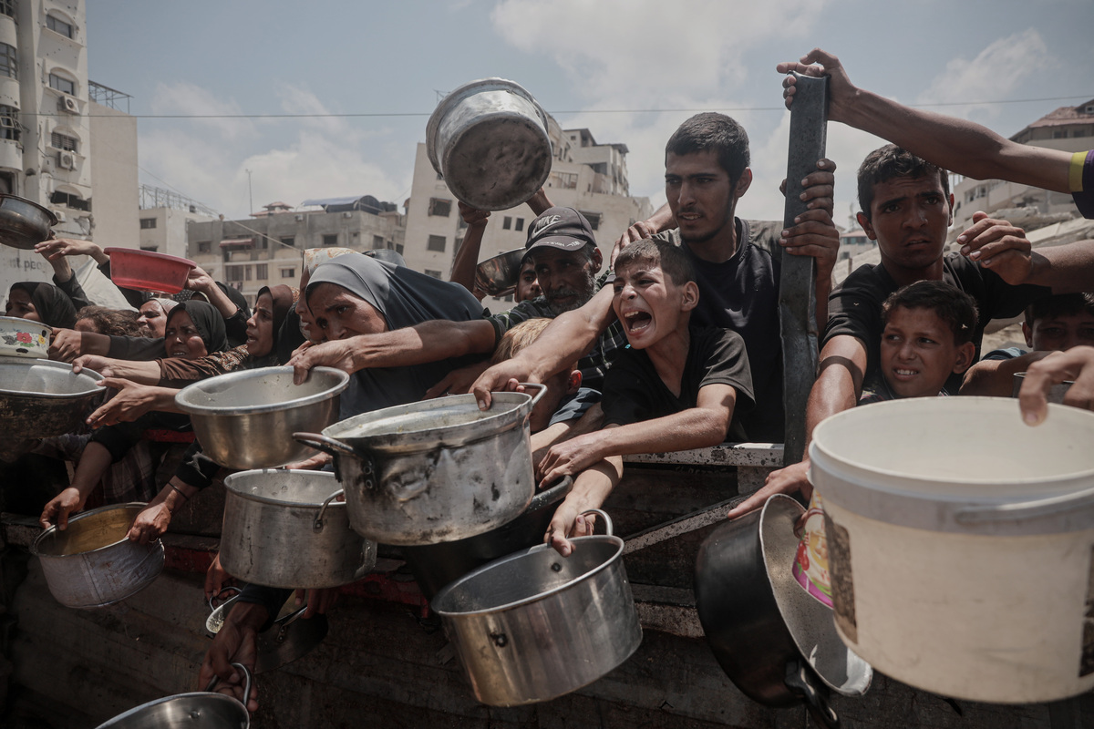 الفلسطينيون ، الذين يواجهون نقصًا في الطعام بسبب الحصار الإسرائيلي والهجمات المستمرة على قطاع غزة ، يجتمعون مع الأواني والمقالي كمؤسسة خيرية يوزع وجبات في مدينة غزة الغربية ، غزة في 08 أغسطس ، 2025 (عبد الله أبو ريش - وكالة أندولو))