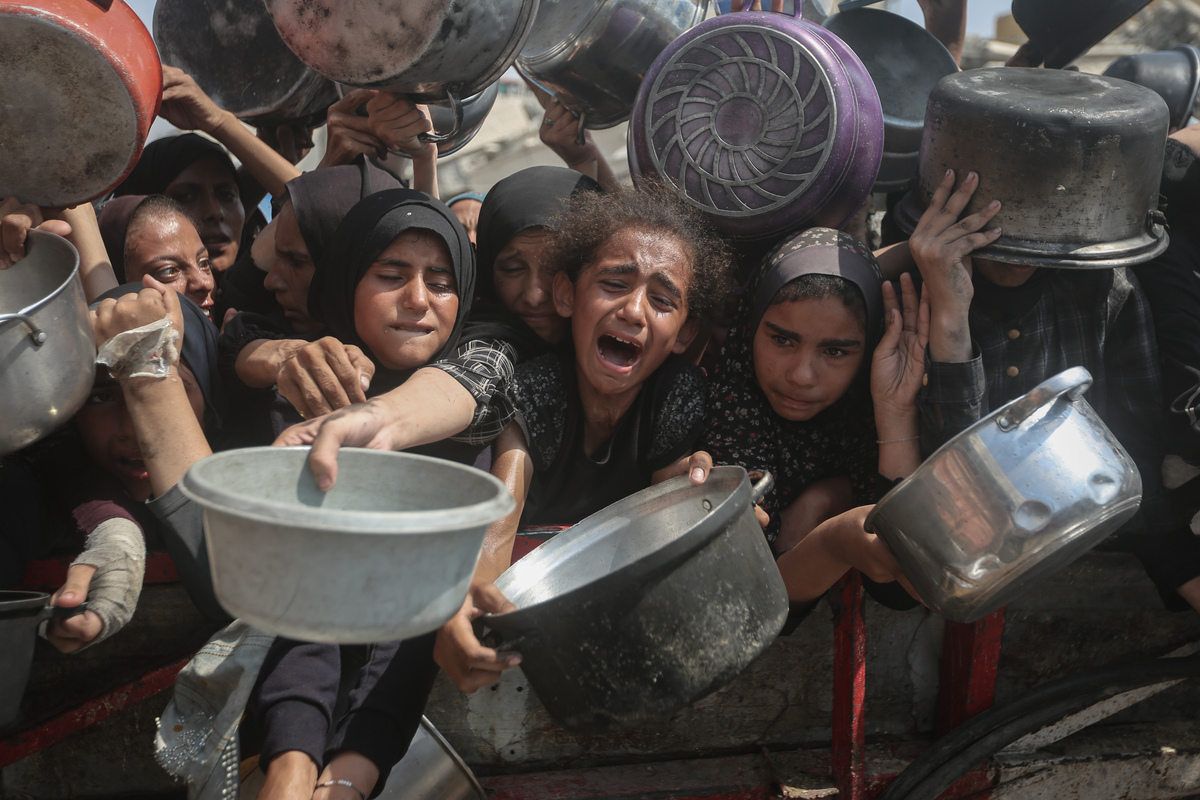 الجوعين الفلسطينيين بما في ذلك النساء والأطفال الذين يحملون الأواني ينتظرون لتلقي الطعام الموزعة من قبل منظمة خيرية حيث تواصل إسرائيل منع المساعدات الإنسانية من الوصول إلى قطاع غزة في 10 أغسطس 2025.