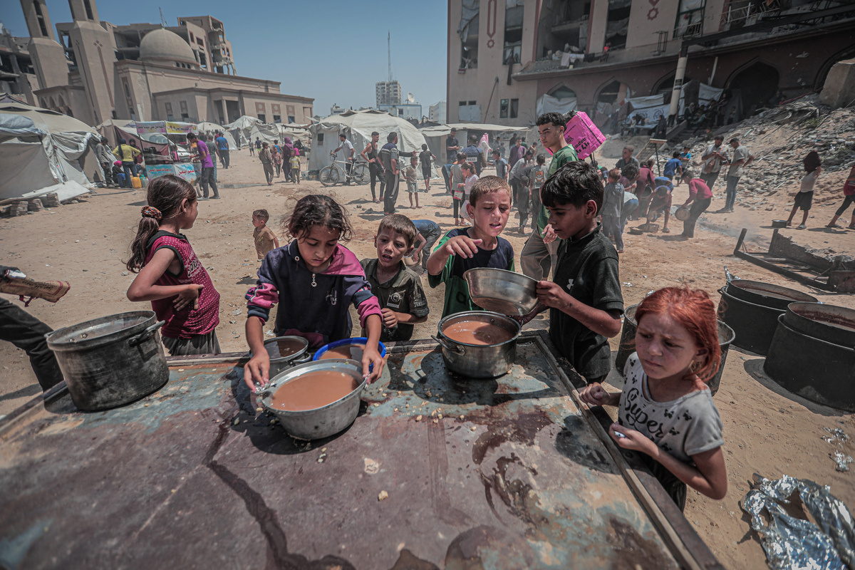 يوزع الفلسطينيون ، بما في ذلك الأطفال ، كقوة خيرية ، الطعام في مدينة غزة ، حيث يواجه السكان صعوبات في الوصول إلى الإمدادات الأساسية وسط الحصار والهجمات الإسرائيلية المستمرة ، في 16 أغسطس 2025.