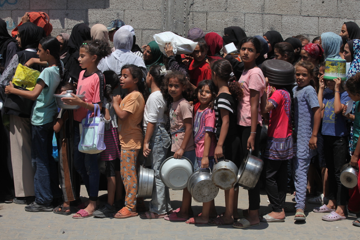 فلسطينيون ، بمن فيهم الأطفال ، الذين يكافحون للوصول إلى الطعام بسبب الحصار الإسرائيلي والهجمات المستمرة على قطاع غزة ، ينتظرون في طابور لتلقي وجبات ساخنة وزعتها المنظمة الخيرية في معسكر نوسيرات للاجئين في دير بالة ، غزة في 18 أغسطس ، 2025.