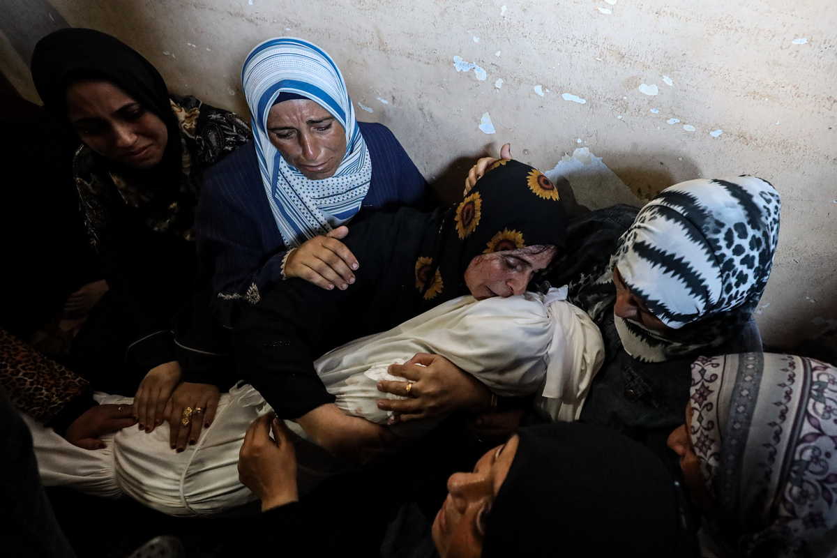 امرأة تبكي بينما كانت تعانق جثة فلسطينية ملفوفة في كفن كأقارب للفلسطينيين ، بمن فيهم الأطفال ، الذين ماتوا نتيجة لهجمات إسرائيلية على أجزاء مختلفة من مدينة غزة ، تم نقل جثث الموتى من مستشفى الشيفا في مدينة غزة في غزة في 24 أغسطس ، 2025.