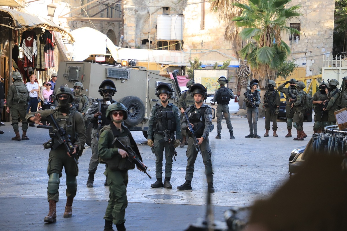 القوات الإسرائيلية تقف حارسًا لأن المستوطنين اليهود غير الشرعيين غزوا منطقة المدينة القديمة في الخليل ، الضفة الغربية في 20 سبتمبر 2025.