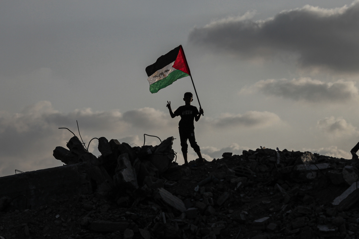 ترفع مجموعة من الأطفال الفلسطينيين في معسكر بوريك العلم الفلسطيني على أنقاض المباني التي دمرتها الإضرابات الإسرائيلية بعد إعلانات الاعتراف بدولة فلسطين من قبل كندا وأستراليا والمملكة المتحدة والبرتغال ، في 22 سبتمبر 2025 ، في مدينة غزة ، غزة. (Moiz Salhi - Anadolu Agency)