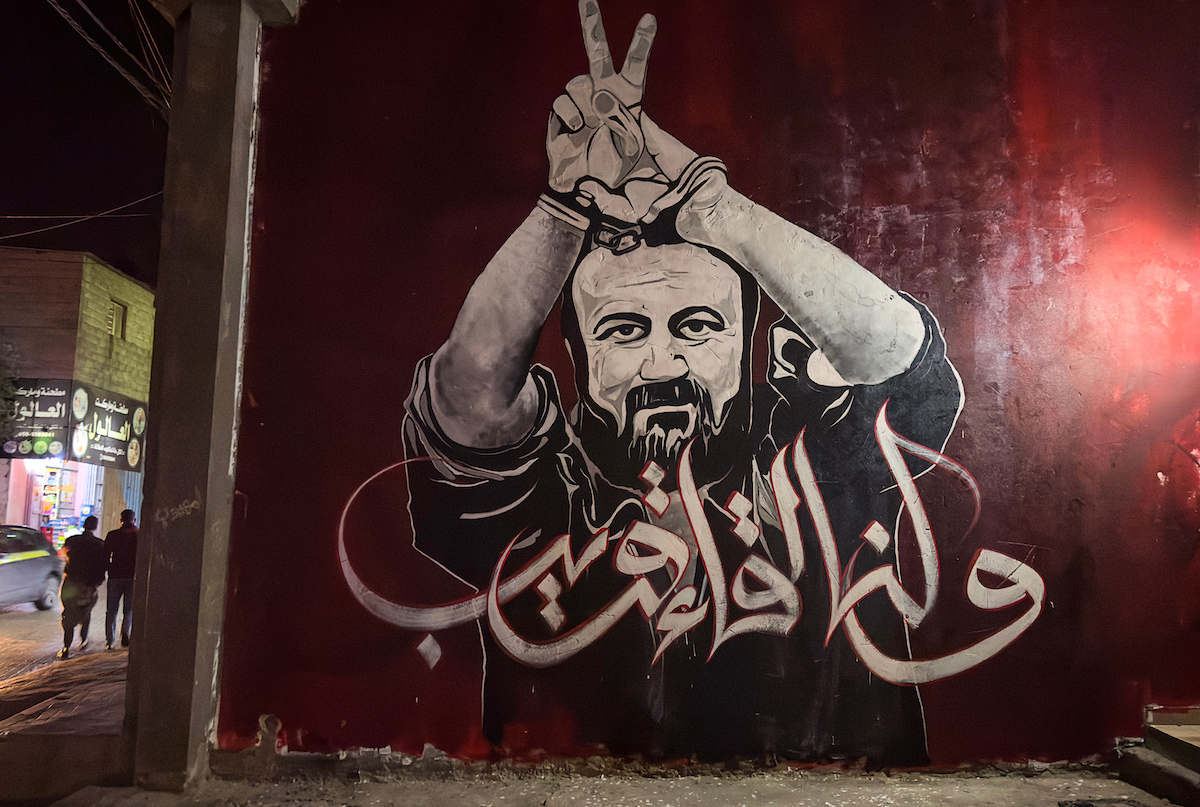 يظهر الفنانون الفلسطينيون من قبل لوحة جدارية سجن زعيم فاتح مروان بارغوتي ، في معسكر جاباليا للاجئين في قطاع غزة الشمالي في 13 أبريل 2023.