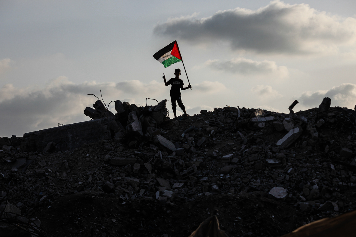 ترفع مجموعة من الأطفال الفلسطينيين في معسكر بوريك العلم الفلسطيني على أنقاض المباني التي دمرتها الإضرابات الإسرائيلية بعد إعلانات الاعتراف بدولة فلسطين من قبل كندا وأستراليا والمملكة المتحدة والبرتغال ، في 22 سبتمبر 2025 ، في مدينة غزة ، غزة. (Moiz Salhi - Anadolu Agency)