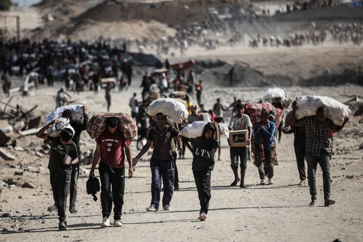 فلسطينيون يحملون أكياس وصناديق من المساعدات الغذائية في منطقة نتساريم في غزة، حيث تجمعت الحشود عند نقطة التوزيع على الرغم من المخاطر، في 5 أكتوبر، 2025. (Moiz Salhi – Anadolu Agency)