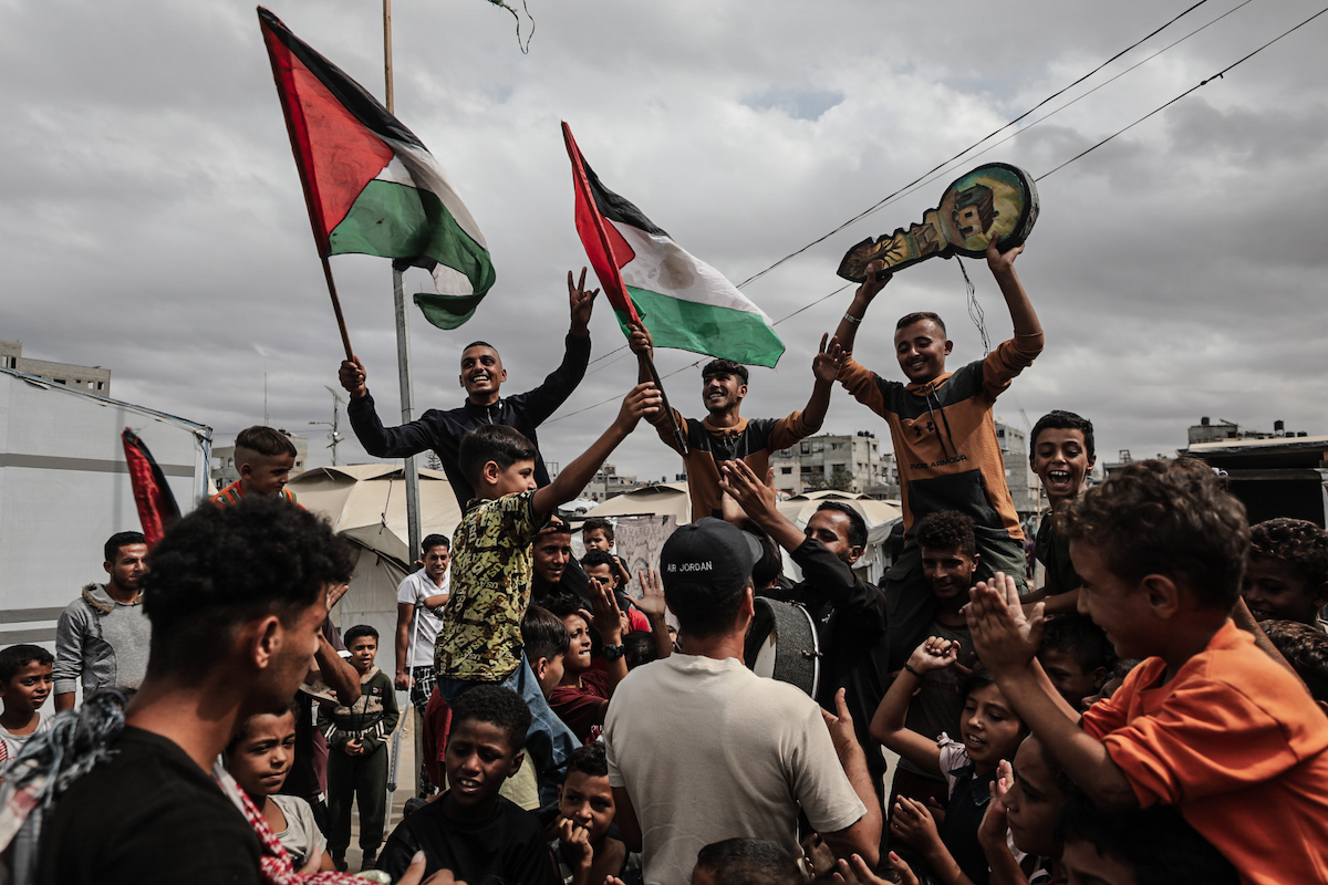 فلسطينيون، بينهم أطفال، متجمعون في مخيم النصيرات للاجئين يحتفلون بالأعلام الفلسطينية بعد إعلان اتفاق وقف إطلاق النار في غزة في 09 أكتوبر 2025 في دير البلح، غزة. ( معز صالحي – وكالة الأناضول)