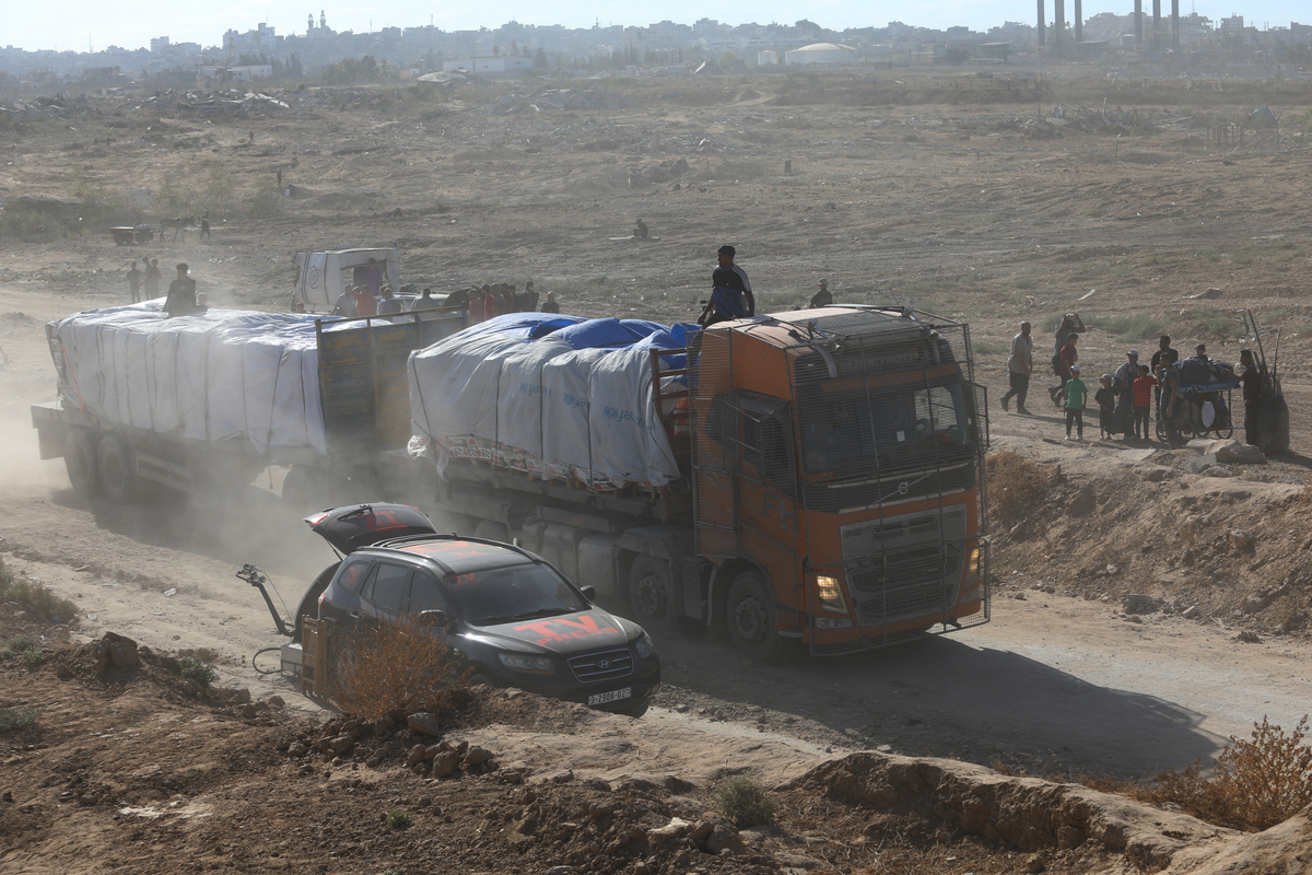 شاحنات محملة بالمواد الغذائية والفواكه المملوكة لتجار فلسطينيين تدخل قطاع غزة عبر شارع صلاح الدين، الواقع جنوب ممر نتساريم، في أعقاب إعلان الجيش الإسرائيلي أن وقف إطلاق النار سيدخل حيز التنفيذ في الساعة 12:00 بالتوقيت المحلي في مدينة غزة، غزة، في 10 أكتوبر، 2025. (أحمد مقادمة - وكالة الأناضول)