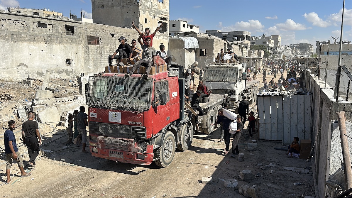 حشد كبير يتجمع لاستقبال شاحنات الإسعافات الأولية التي وصلت إلى غزة بعد وقف إطلاق النار عبر معبر كرم أبو سليم الحدودي في خان يونس، غزة، 12 أكتوبر، 2025. (محمود صباح – وكالة الأناضول)