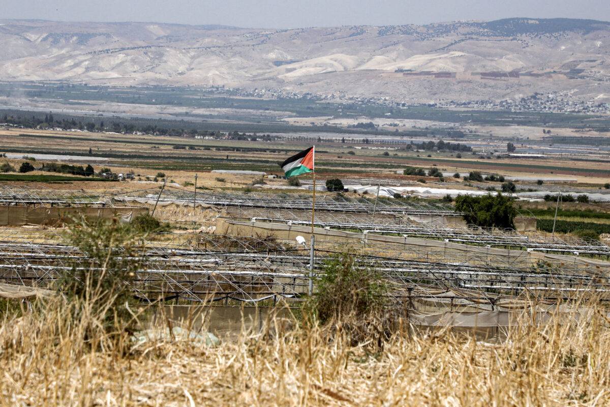 تُظهر هذه الصورة التي التقطت في 21 يونيو 2020 علمًا فلسطينيًا يطير في قرية باردالا في وادي الأردن في الضفة الغربية المحتلة ، مع قرى الأردن شرق نهر الأردن في الخلفية (Jaafar Ashtiyeh/AFP عبر Getty Images)