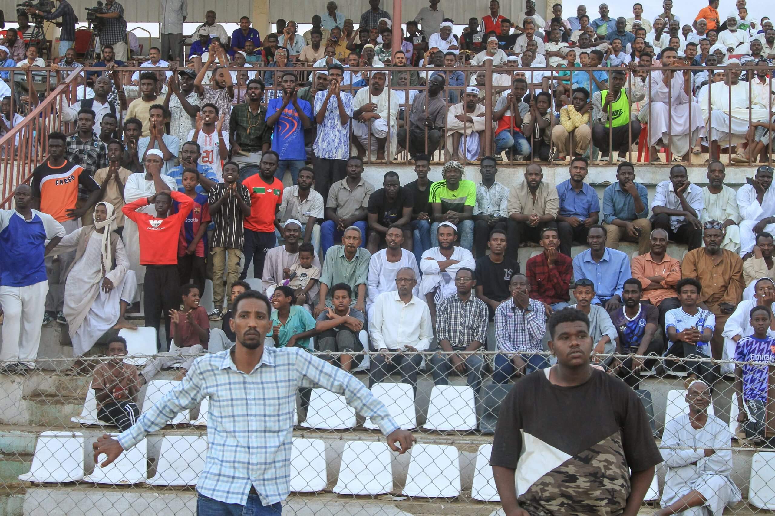 المشجعون والمشجعون يشاهدون مباراة كرة القدم في الدوري السوداني الممتاز بين حي الوادي والهلال أم درمان في ملعب مدينة بربر في بربر بولاية النيل السودانية في 16 يوليو 2025. في بلدة بربر السودانية، على بعد مئات الكيلومترات من الخطوط الأمامية للحرب، يبدو أن ملعبًا متواضعًا يهتز مع هدير مشجعي كرة القدم الذين يقفزون على أقدامهم.