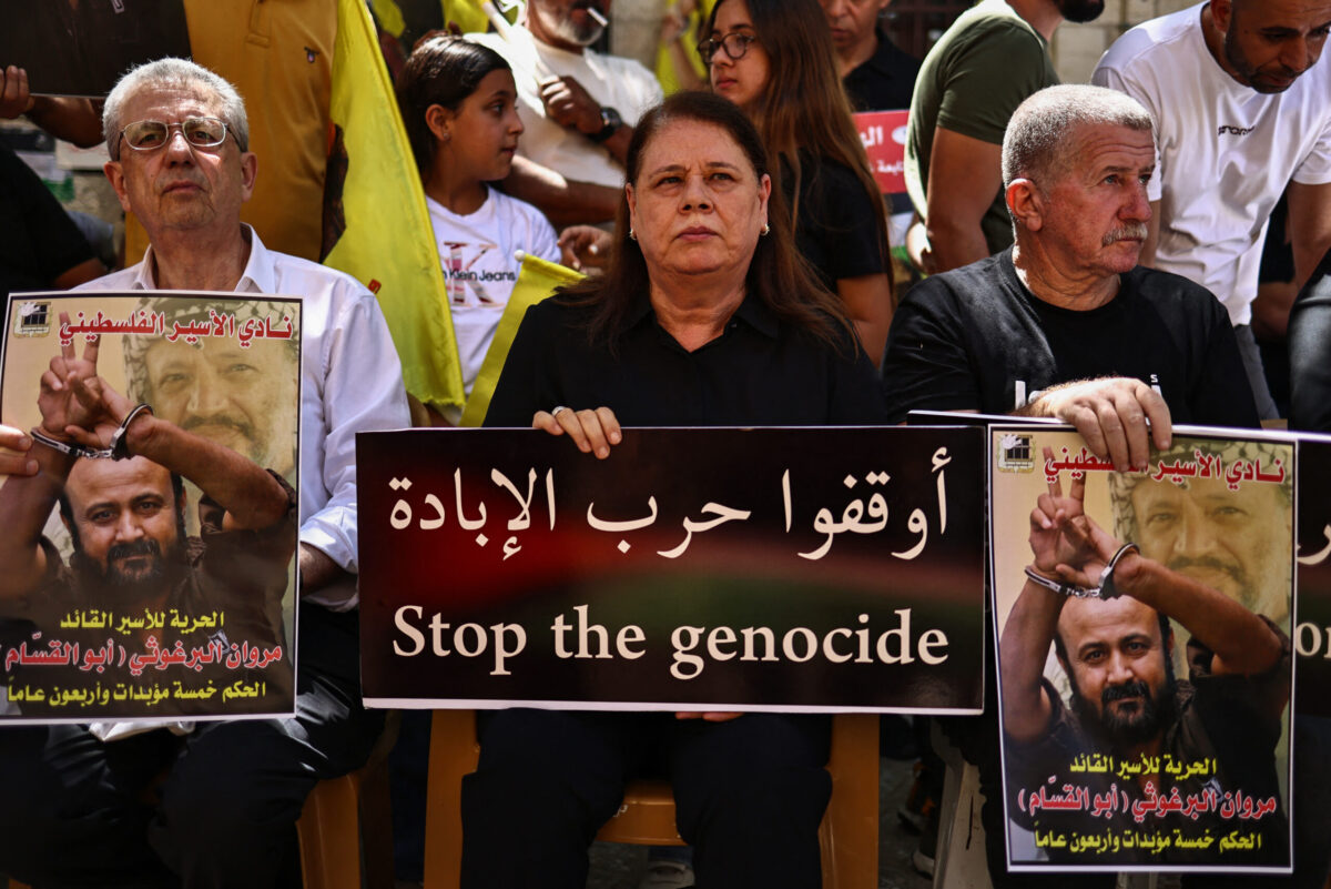 فدوى، زوجة العضو القيادي في حركة فتح الفلسطينية مروان البرغوثي، المعتقل الفلسطيني الأكثر شهرة في السجون الإسرائيلية، ترفع لافتة خلال مسيرة لدعمه في مدينة رام الله بالضفة الغربية المحتلة، حضرها السياسي مصطفى البرغوثي (يسار) والناشط السياسي عمر عساف، 19 أغسطس، 2025. (ZAIN JAAFAR/AFP عبر Getty Images)