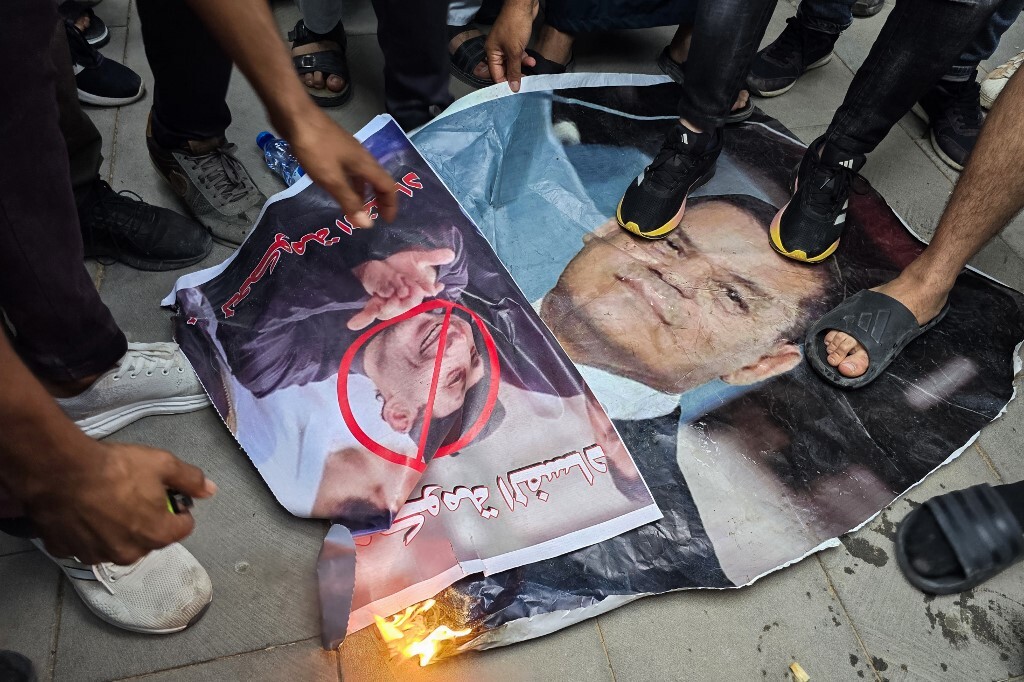 متظاهرون يحرقون صورة رئيس الوزراء الليبي عبد الحميد دبيبة خلال مظاهرة في ساحة الشهداء بطرابلس للمطالبة باستقالته، في 16 مايو 2025 (AFP)